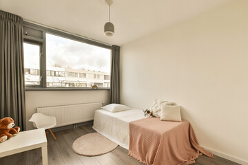 a bedroom with two beds and a teddy bear sitting on the bed in front of the window looking out onto the street