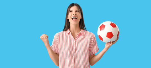 Happy young woman with soccer ball on blue background
