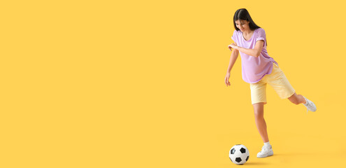 Young woman playing with soccer ball on yellow background with space for text