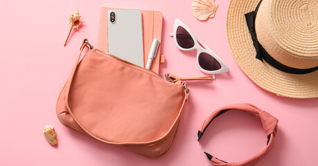 Stylish bag with mobile phone and accessories on pink background