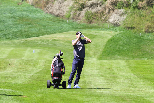 Man golfer with rangefinder on golf course - Powered by Adobe