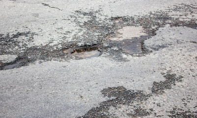 Deep pit on the road. Damaged asphalt.Puddles in potholes on the road. Damaged highway.Pit in the asphalt, destroyed road, destroyed road surface,