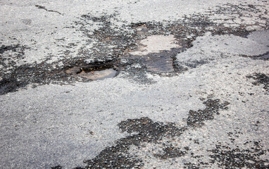Deep pit on the road. Damaged asphalt.Puddles in potholes on the road. Damaged highway.Pit in the asphalt, destroyed road, destroyed road surface,