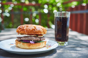 Homemade tasty and juicy beef burger served with cola drink on the vintage white porcelan plate,...