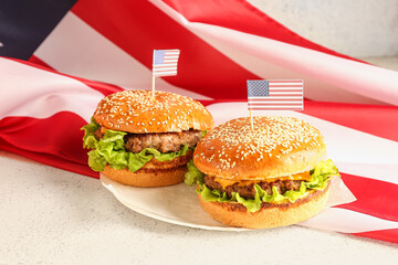 Plate with tasty burgers and American flag on light background. Memorial Day celebration