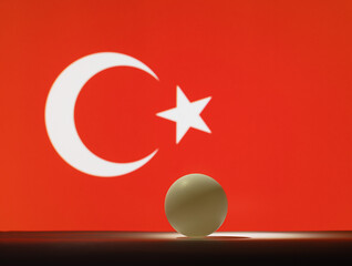 Obraz premium The pingpong ball stands on a surface in front of Turkey flag.