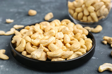 Plate with tasty cashew nuts on blue background