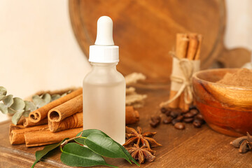 Wooden board with bottle of essential oil, cinnamon sticks and anise stars, closeup