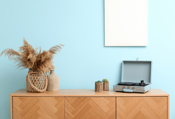 Stylish wooden cabinet with record player near blue wall