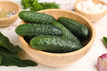 Bowl with fresh cucumbers for preservation on light background
