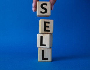 Sell symbol. Concept word Sell on wooden cubes. Businessman hand. Beautiful blue background. Business and Sell concept. Copy space.