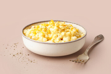 Bowl of tasty Italian pasta with Cheddar cheese on beige background