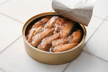 Canned smoked sprats on white tile background