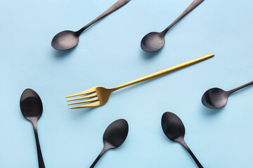 Stylish spoons and fork on blue background