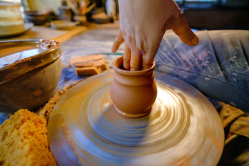 ceramics, workshop, ceramic art concept - close-up of man's hands forming a new vessel, man's fingers working with potter's wheel and raw edge, frontal close-up.