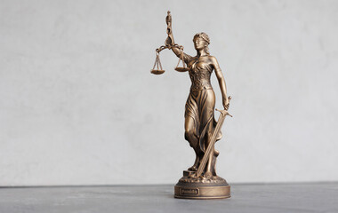 themis goddess of justice statuette on light gray background. symbol of law with scales sword in...