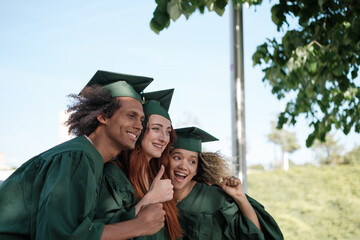 Three friends taking a photo celebrating their university graduation with the border suit. Concept: graduation, university, studies