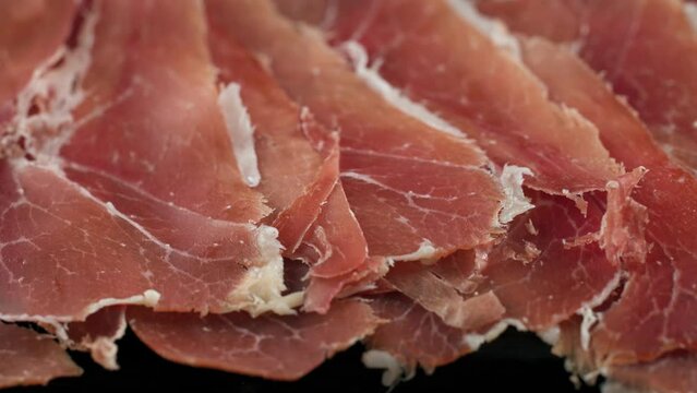 plate of sliced spanish iberico ham on wooden table background