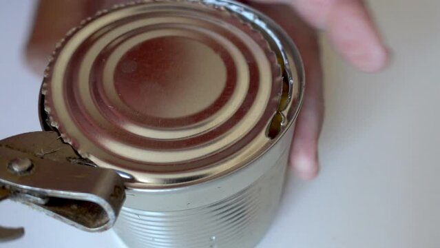 Hand opens tin can with corn in time lapse