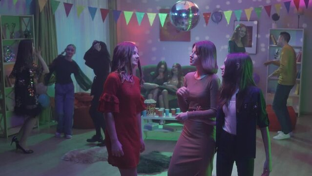 At the party, teenagers dance in separate groups. A group of three girls are dancing separately, the girls are talking, smiling. Dance of three girlfriends close up. HDR BT2020 HLG Material.