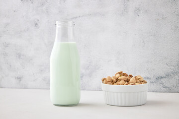 Homemade vegetable milk from pistachio nuts. Pistachio milk in a bottle on a gray concrete table. Ideal for vegans. place for text