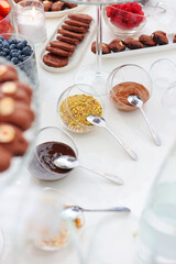 Various sweet sauces and chopped nuts on the table. Field service at parties. The concept of catering organization. Selective focus.Vertical photo.