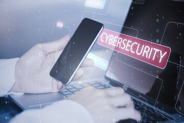 Close up of hand using cellphone and laptop with glowing hacking hologram and binary code lines on blurry background. Cybersecurity, firewall and software protection concept. Double exposure.