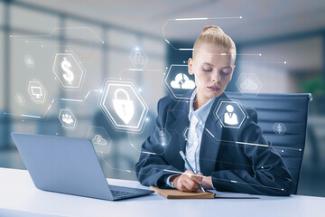 Attractive businesswoman at desk with devices and glowing web security hologram with other icons on blurry office interior background. Digital interface and protection concept. Double exposure.