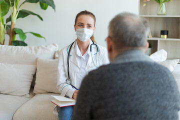 Fototapeta premium Female doctor examining older senior man in doctor office or at home. Old man patient and doctor have consultation in hospital room. Medicine healthcare medical checkup. Visit to doctor