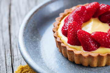 Strawberry tart, popular French pastry or Italian. Served on a plate placed on a rustic wooden table. Seasonal dessert. 