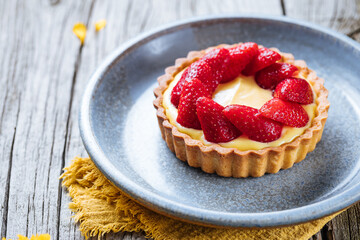 Strawberry tart, popular French pastry or Italian. Served on a plate placed on a rustic wooden table. Seasonal dessert. 