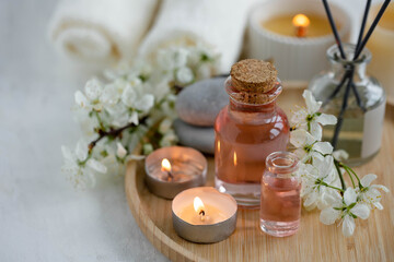 Aromatherapy, home decor concept. Glass perfume bottle, elegant composition with spring flowers. Burning candles, spa setting, essential oils, organic pure aromatic ingredients, atmosphere of relax