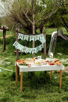 catering for the first birthday. inscription, happy birthday. holiday table with food and snacks, holiday table, concept in rustic style, picnic in nature in honor of the birthday