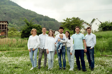 portrait of a happy big family in nature. family of three generations. a group of close people. European family. mom and dad hold son next to grandma and grandpa and siblings