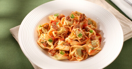 tortelloni with bolognese sauce. classic Italian pasta with spinach and ricotta in tomato-meat sauce. dish of mediterranean cuisine on a green background. food on the table on a sunny day.