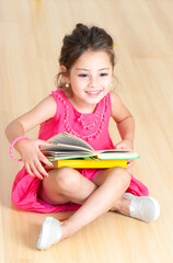 girl with books sitting on the floor in kindergarten