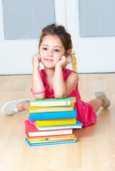 girl with books sitting on the floor in kindergarten