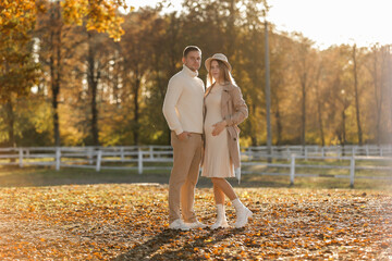 Fototapeta premium Young stylish couple lovers are hugging in the autumn park. Lovely romantic moment between man and woman in love. Happy family. Love, youth, happiness concept.