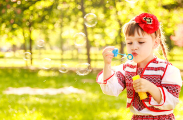 Girl blowing soap bubbles. A girl with a red poppy in her hair. A child in a national Ukrainian costume. Children in Ukraine.

