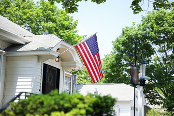 US flag proudly displayed in front of an American house symbolizes patriotism, national identity, and love for one's country. It represents unity, freedom, and the values upon which the United States 