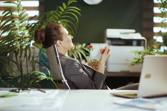 relaxed female employee in green office eating salad
