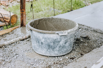 A bowl, a bucket, a concrete mixer in concrete, cement stands on stones at a construction site....