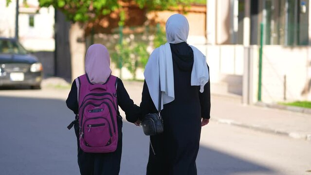 A woman takes her little daughter to school in the morning.