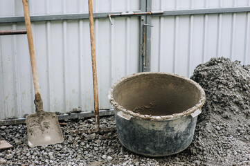 Construction tools: a bucket, a shovel, a rake, a concrete mixer in concrete, cement stand on...