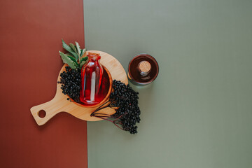 Elderberry syrup and Elderberry berries on a combined brown and green background.Sambucus syrup in...