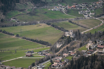 Obraz premium White Stone Castle in the alpine mountains.Landmark and castles of Austria.Castle in the town of Matrei ins Tyrol,Austria. City at the foot of the mountains. view from above.