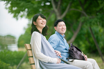 公園で休憩する妊婦と夫
