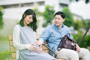 公園で休憩する妊婦と夫