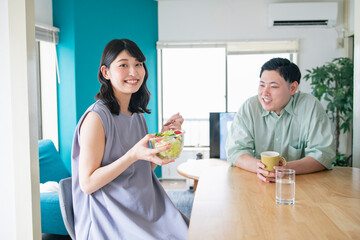 昼食を食べる妊婦と彼女を見守る夫
