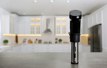 Sous vide cooker on light grey table in kitchen, space for text. Thermal immersion circulator